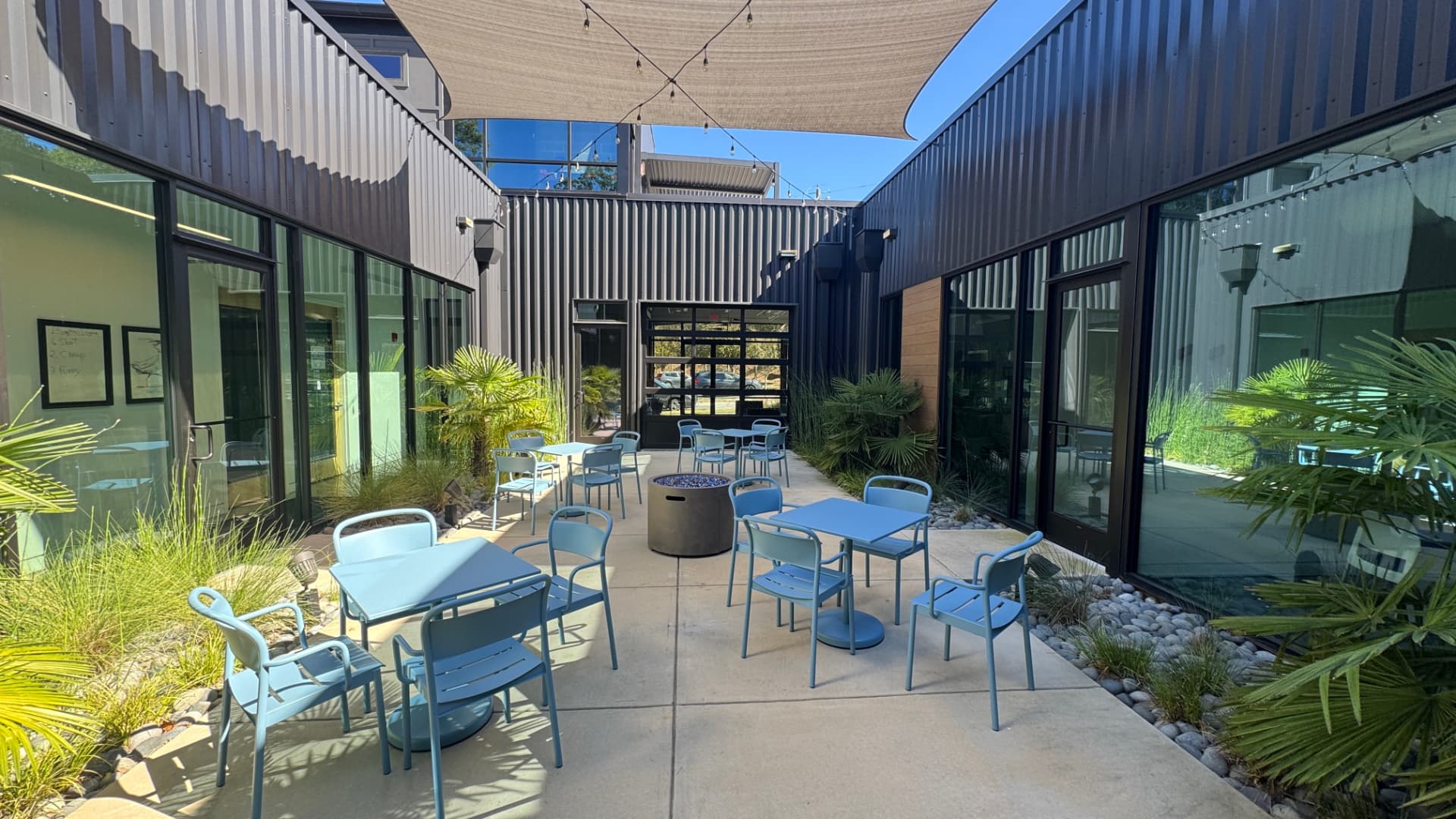Shared outdoor courtyard with tables, chairs and shade sail