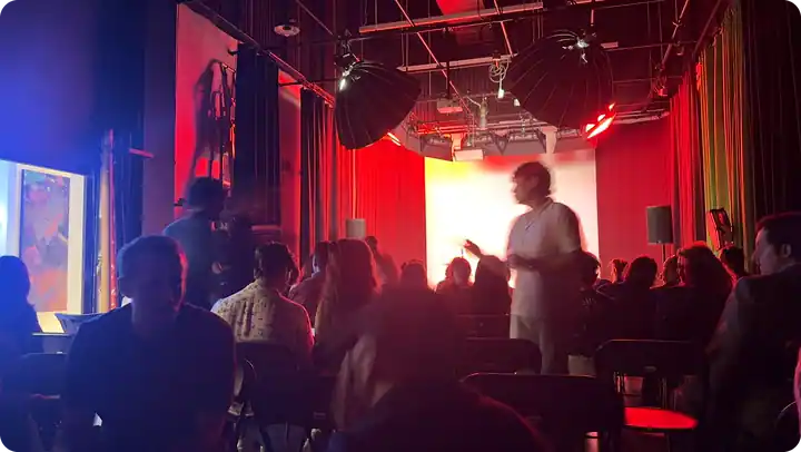 A full audience at an event on The Stage, lit in red and blue